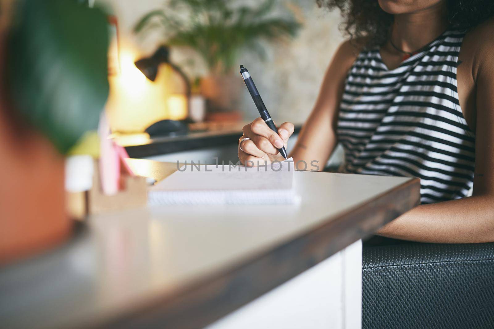 Shot of an attractive young african woman sitting alone and making a note in her home office - Stock photo