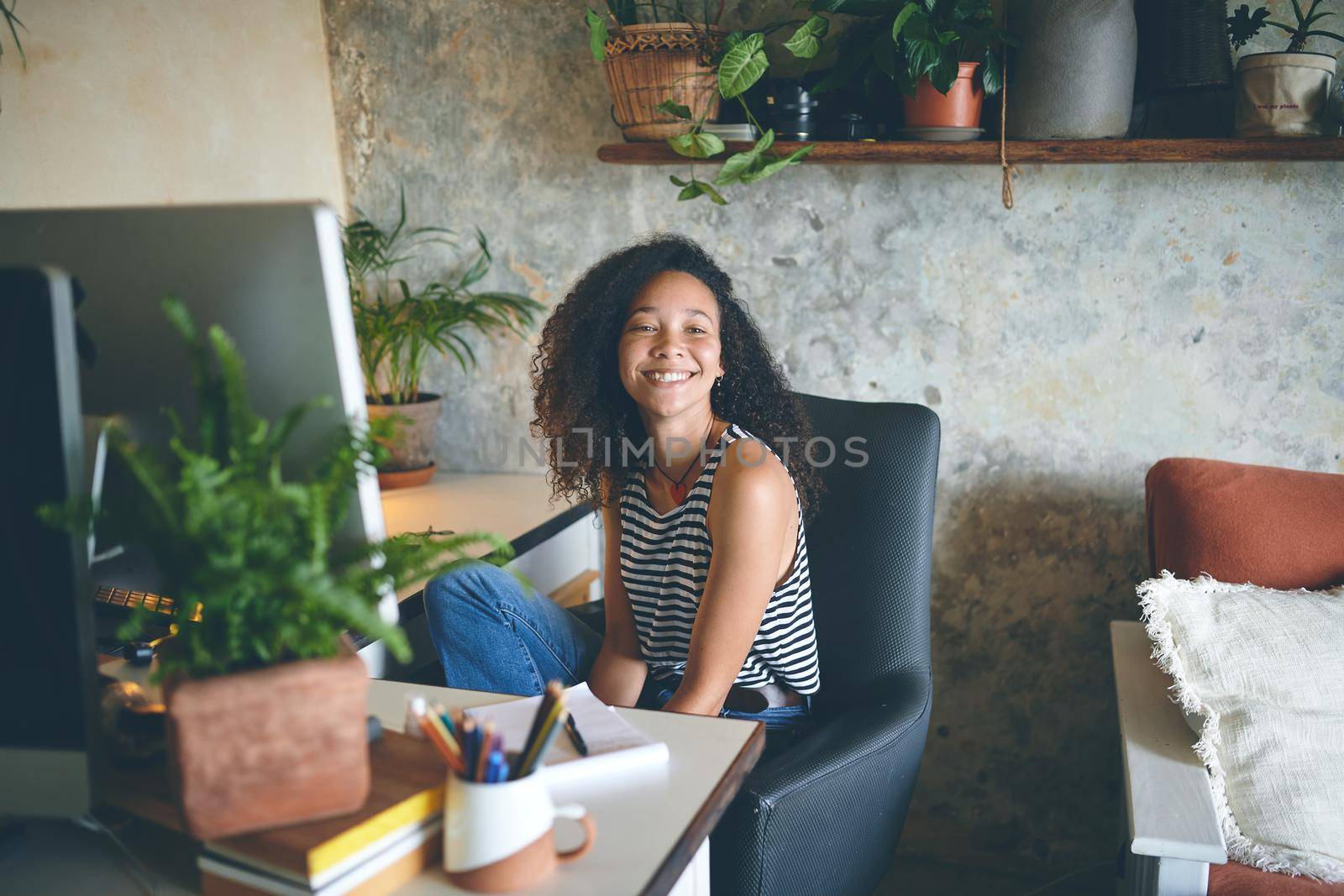 Shot of an attractive young woman sitting at her home desk smiling at the camera - Stock Photo