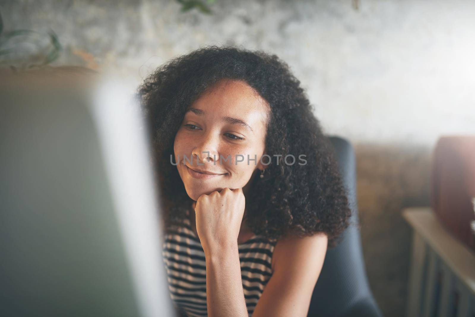 Shot of an attractive young african woman sitting alone and using her desktop pc while working from home stock photo