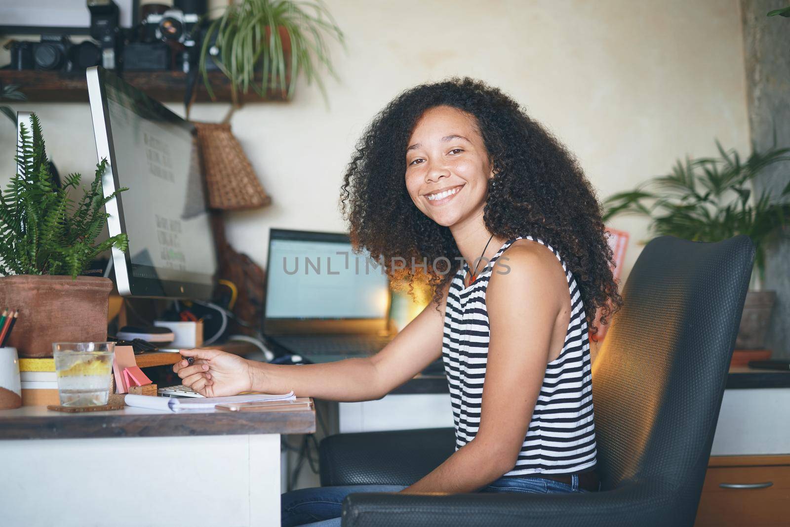 Shot of an attractive young african woman sitting alone and making notes in her home office - stock photo