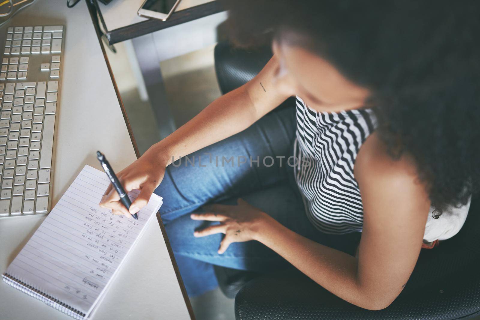 Shot of an attractive young african woman sitting alone and making a note while working from home stock photo