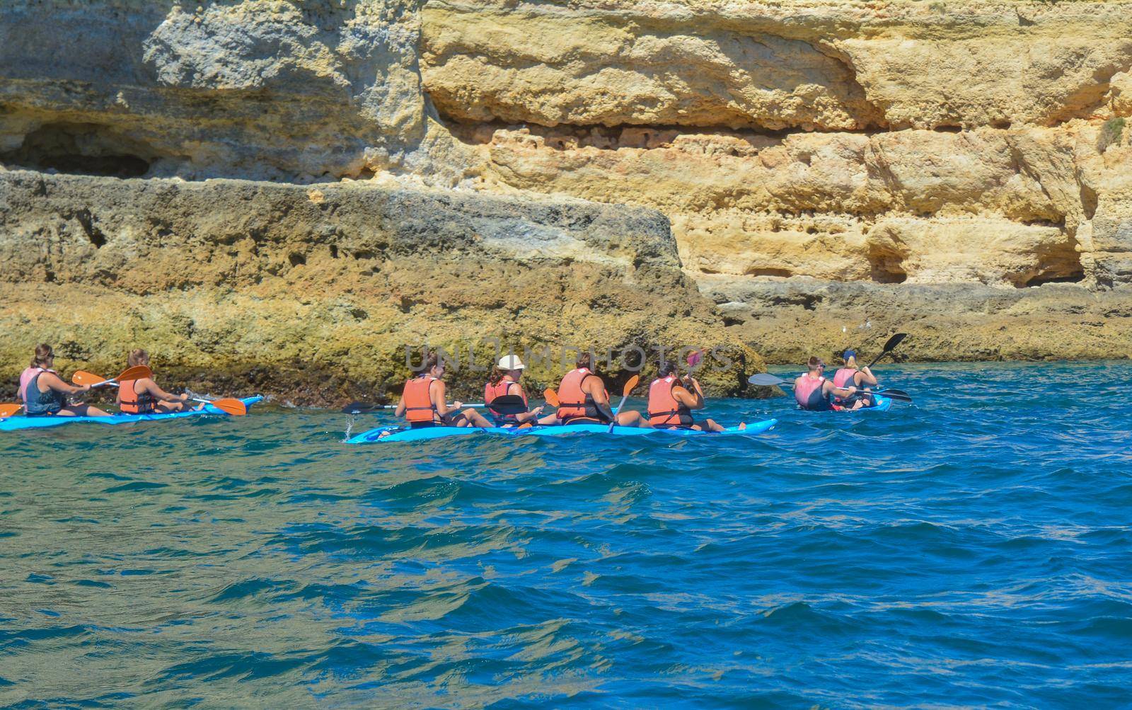 Group of people on canoe in the ocean with mountains. Kayaks.