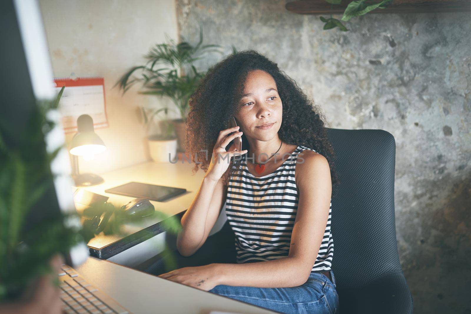 Shot of an attractive young african woman sitting alone and using technology while working from home stock photo