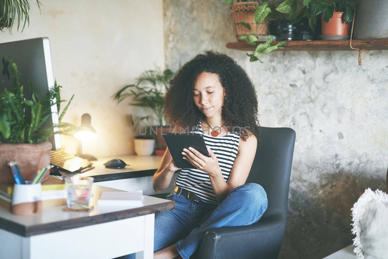 Shot of an attractive young woman sitting alone and using her tablet while working from home stock photo