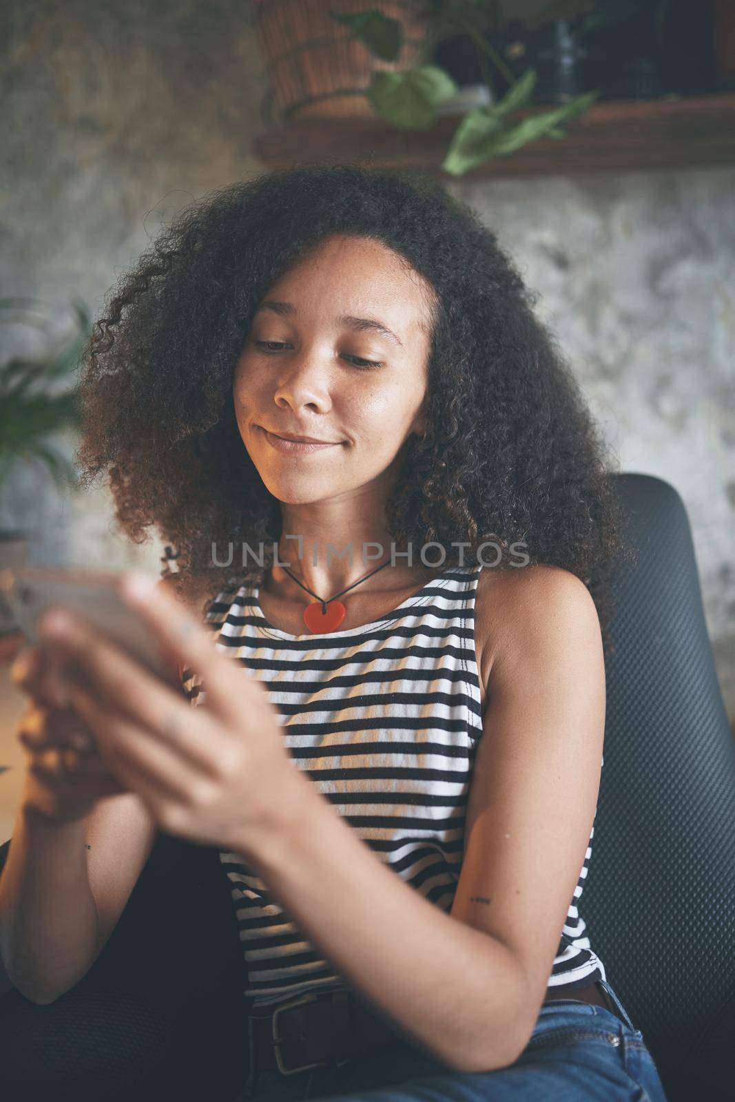 Shot of an attractive young african woman sitting alone and using technology while working from home stock photo
