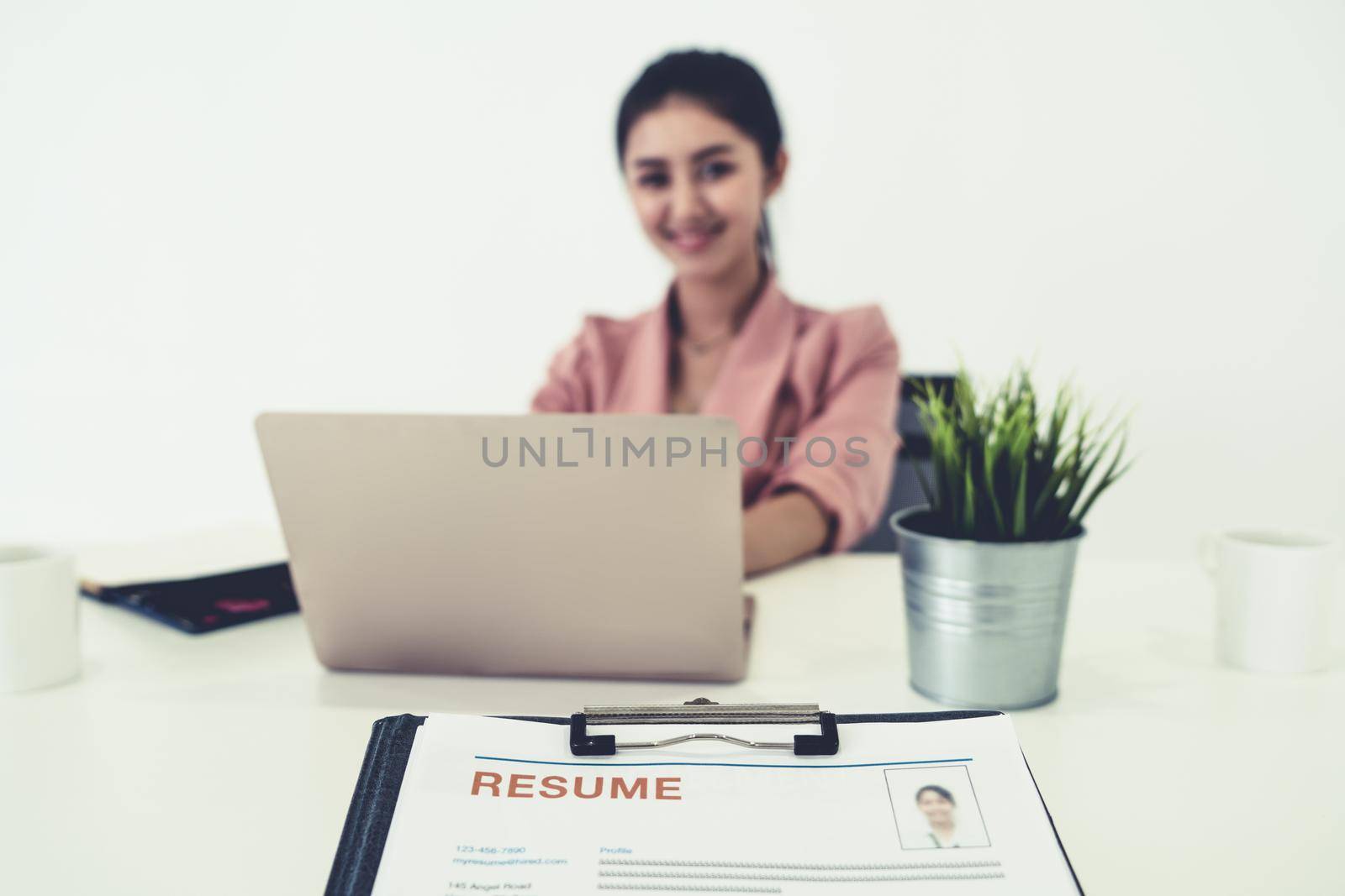 Resume or CV (curriculum vitae) document paper sent to businesswoman from human resources department sitting at table in office. Job application and hiring concept.