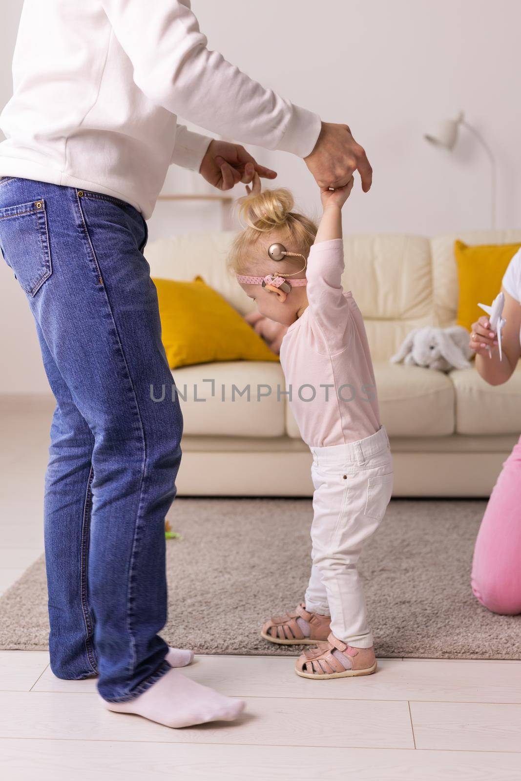 Happy child girl with cochlear implant having fun with her father - hearing aid for deaf and innovative health technology