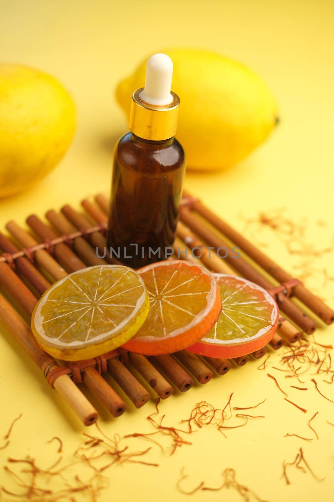 Essential oil bottle and lemon on yellow background ,