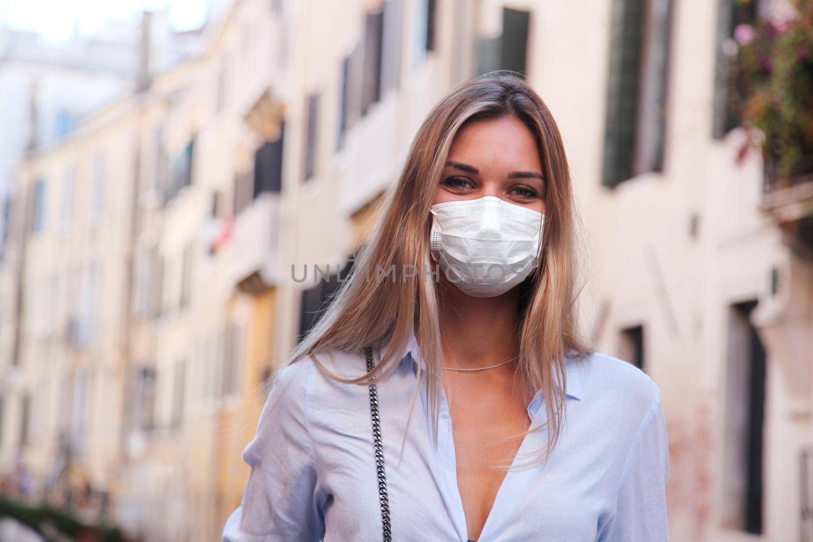 Beautiful tourist woman with corona virus mask at the island of Venice in Italy by Taut