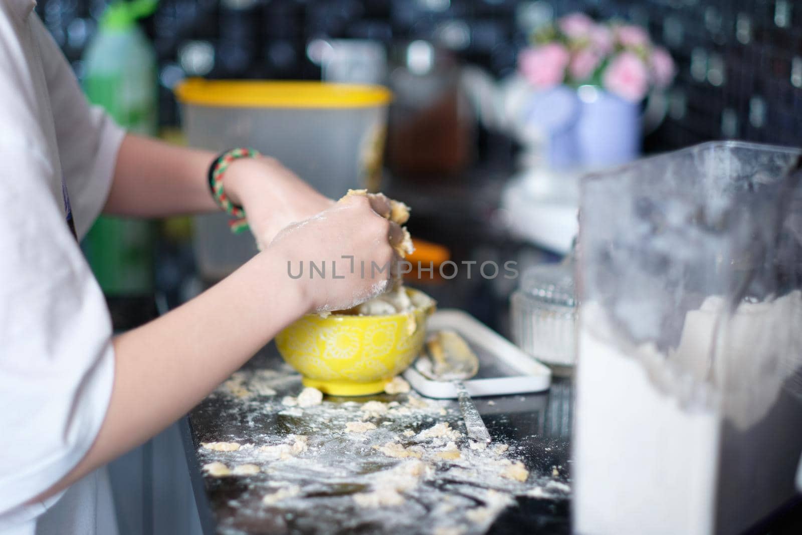 The girl's hands make dough in the kitchen at home.