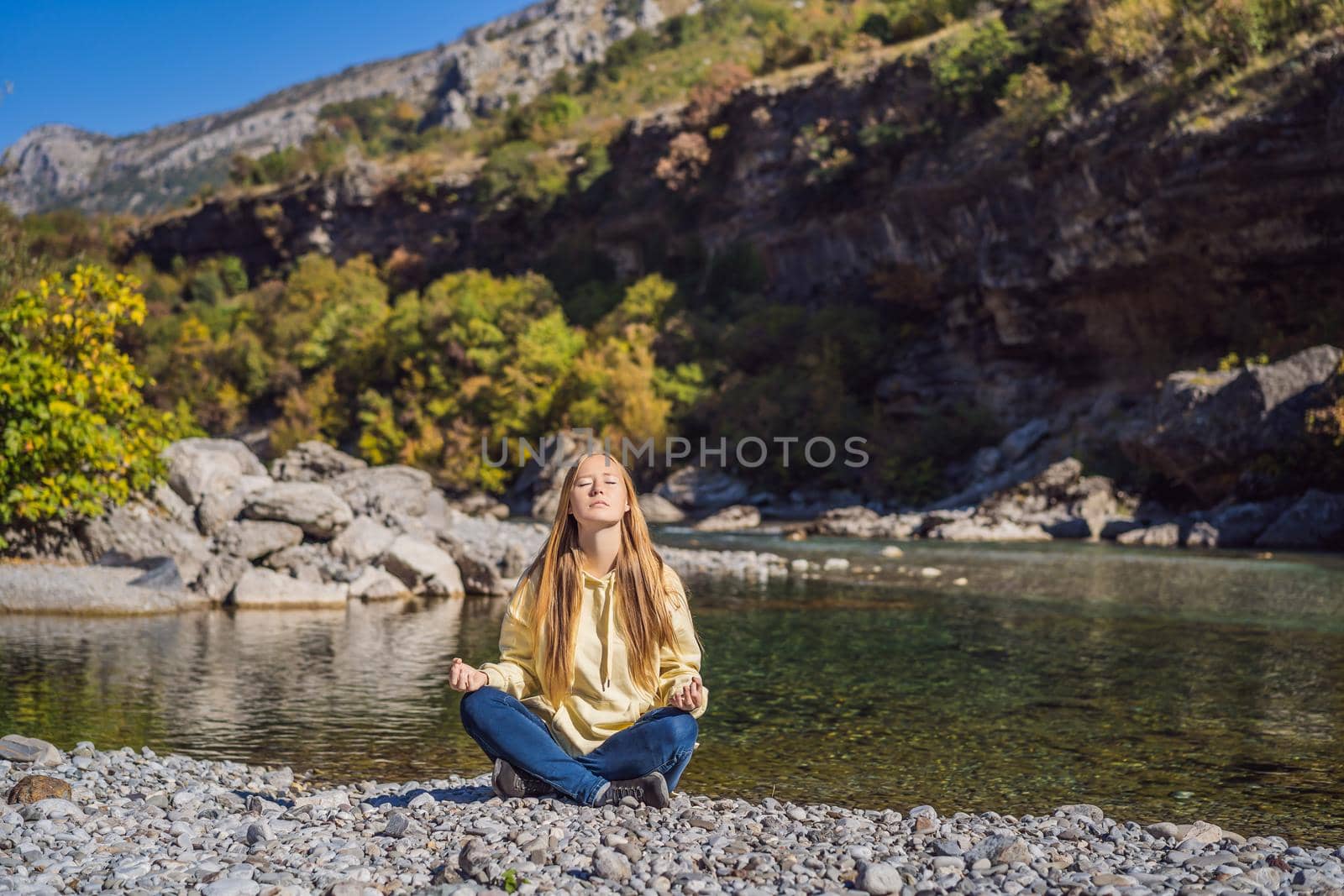 Montenegro. Woman tourist meditates on the background of Clean clear turquoise water of river Moraca in green moraca canyon nature landscape. Travel around Montenegro concept.