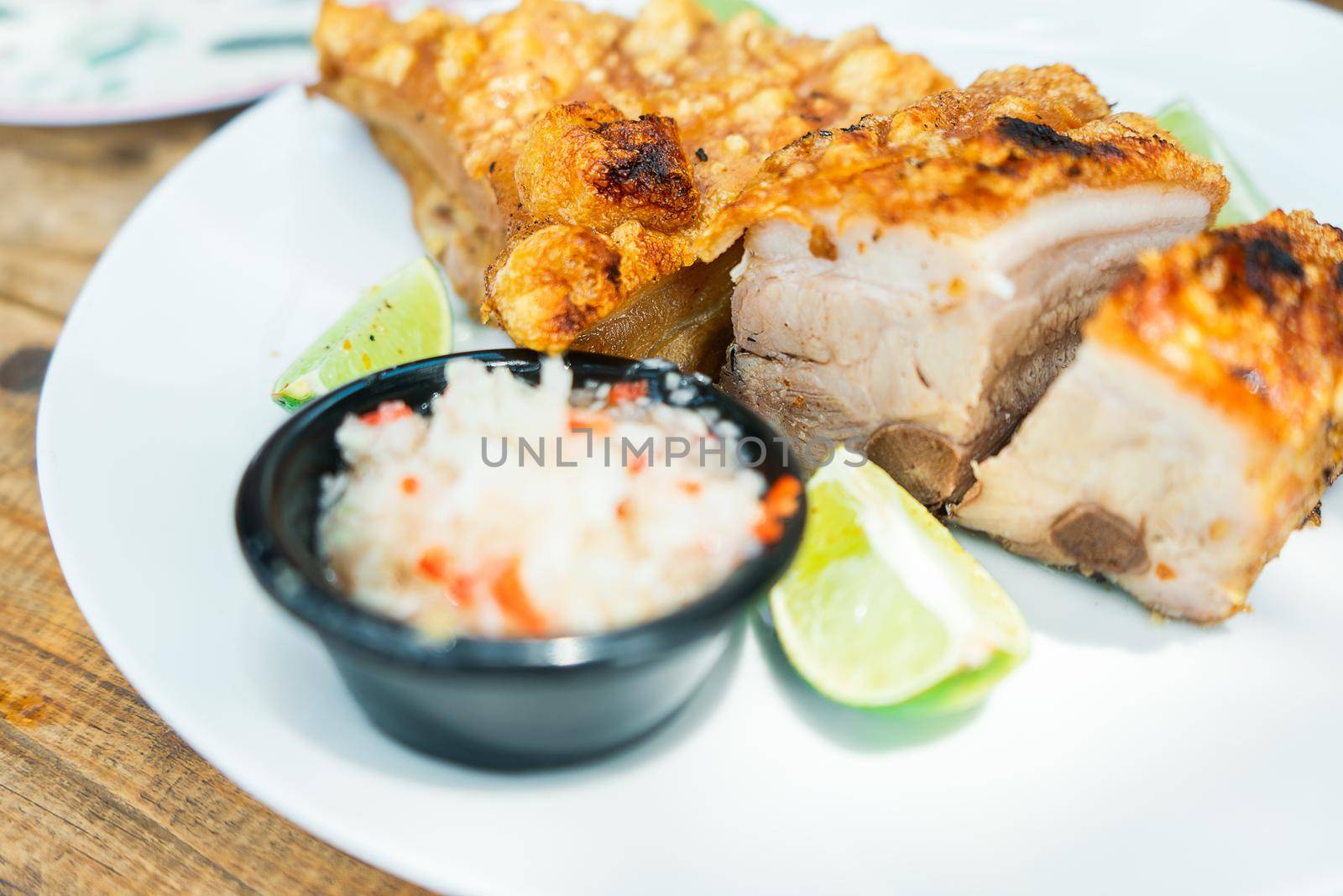 45 degree photo of a plate with lime fried pork shoulder and spicy onion salad. Traditional from Latin American by cfalvarez