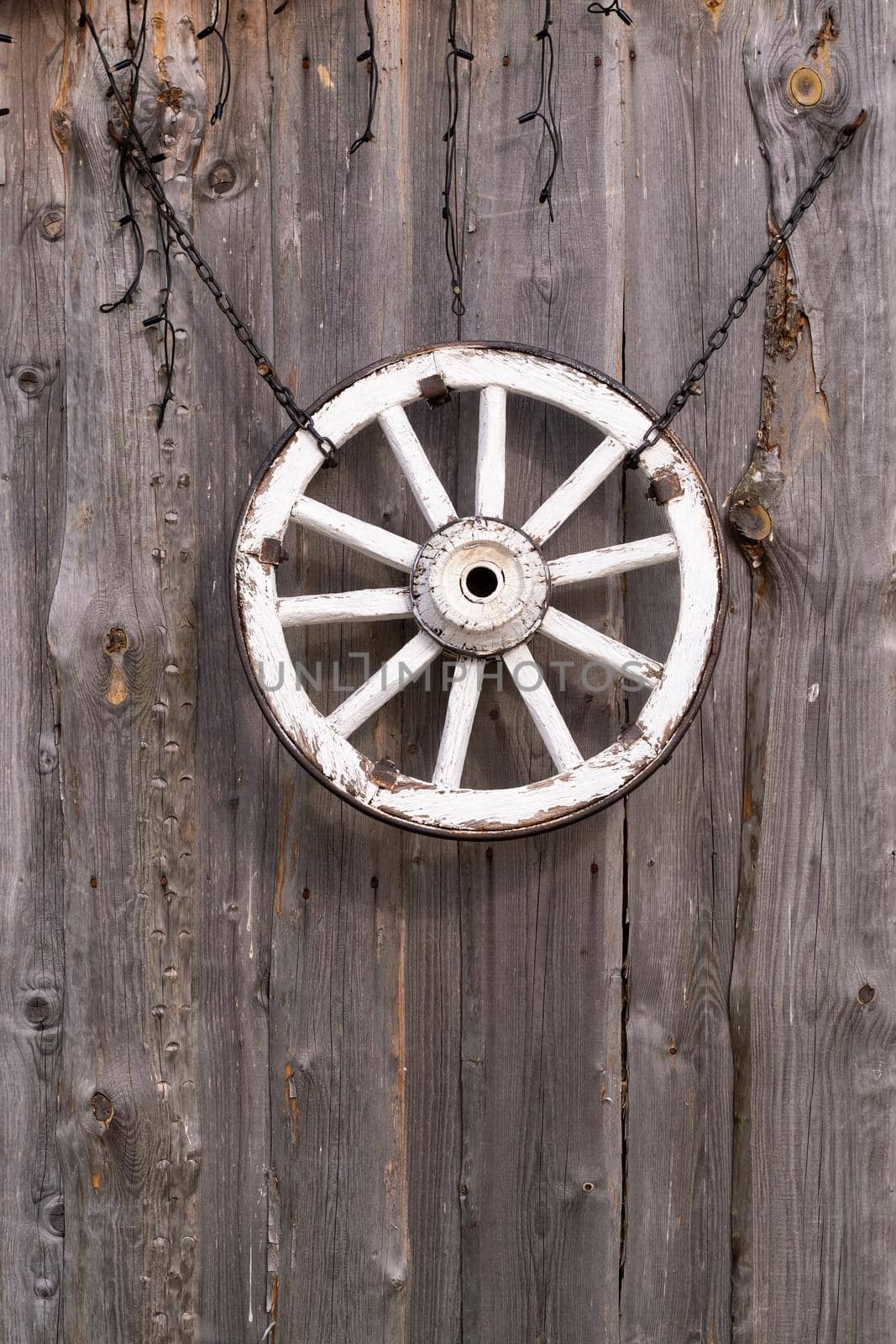 An old wooden carriage wheel hanging on the barn wall by Lobachad