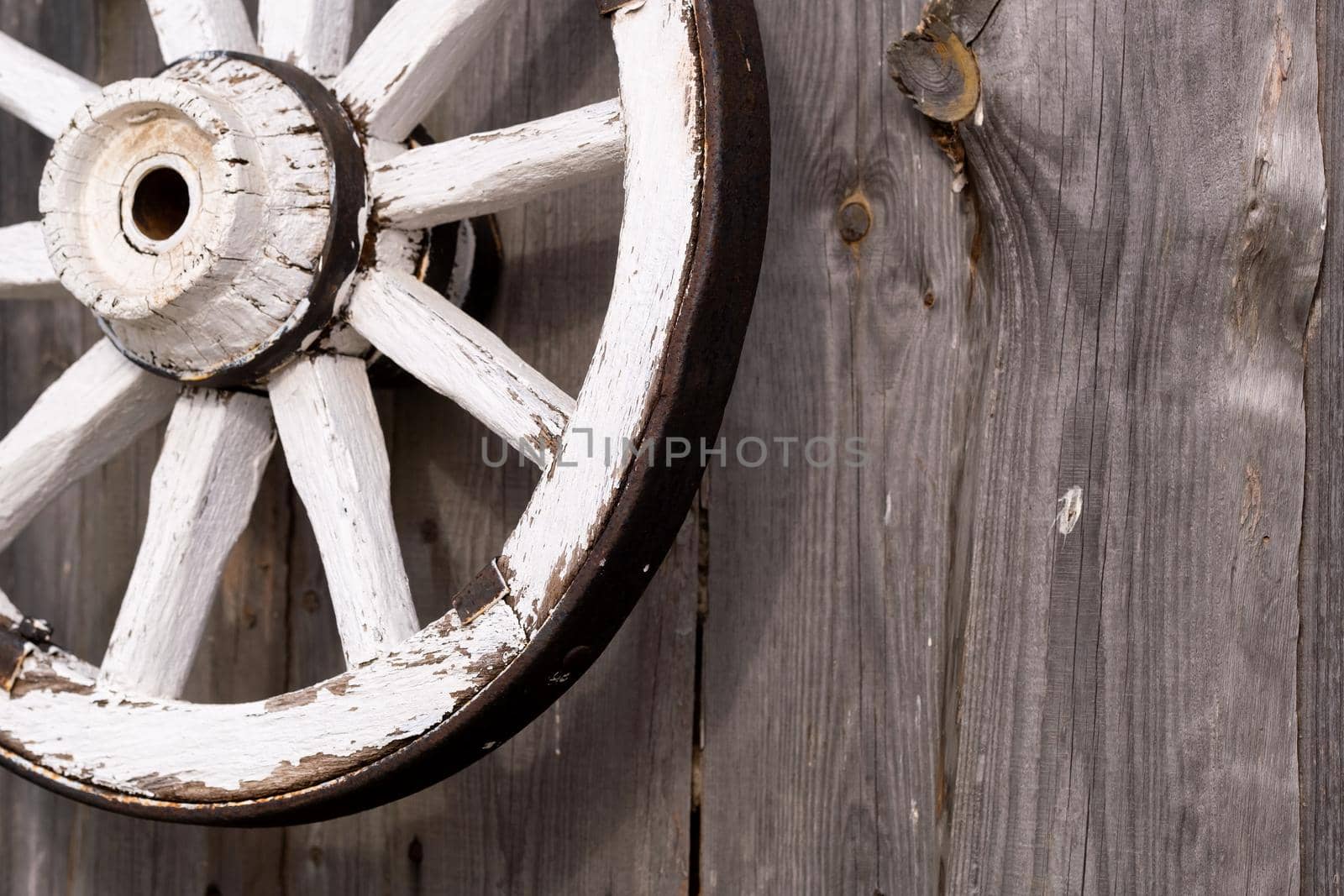 An old wooden carriage wheel hanging on the barn wall.