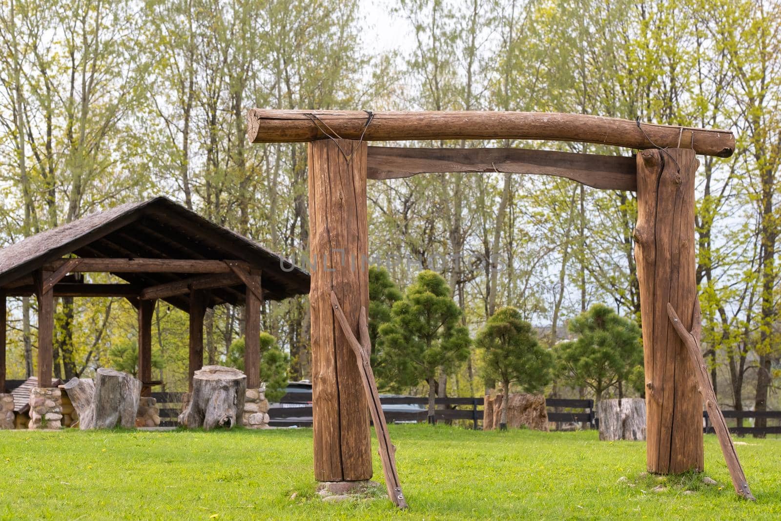 A wooden arch and a wooden gazebo standing on the territory next to the estate.