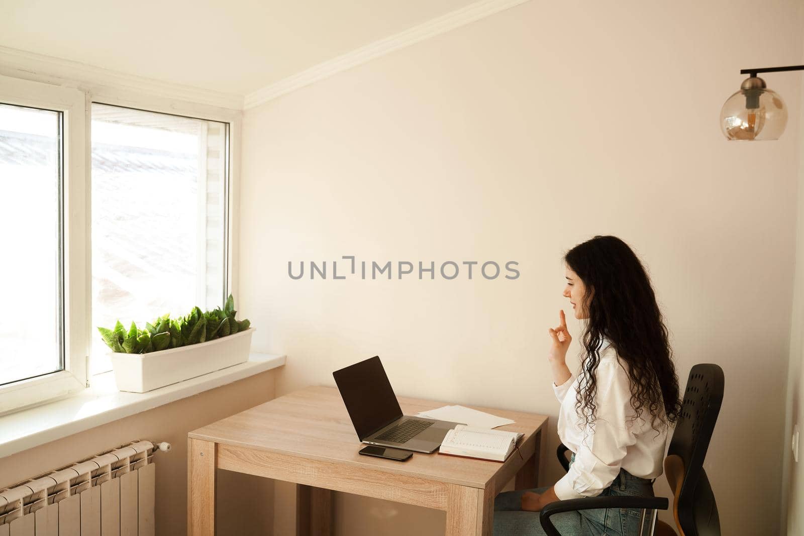 Positive caucasian girl enjoying friendly video call on laptop computer using web camera for communicating. Young woman waves her hand and greets her friends by video call