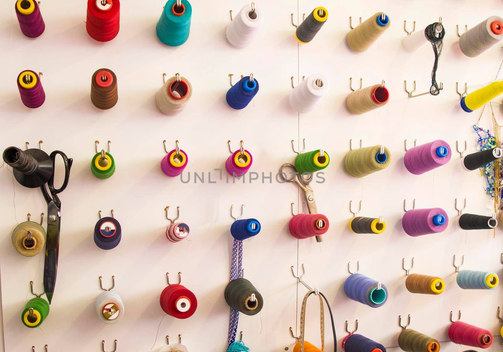 Multicolored coils and scissors on the wall. Workplace seamstresses