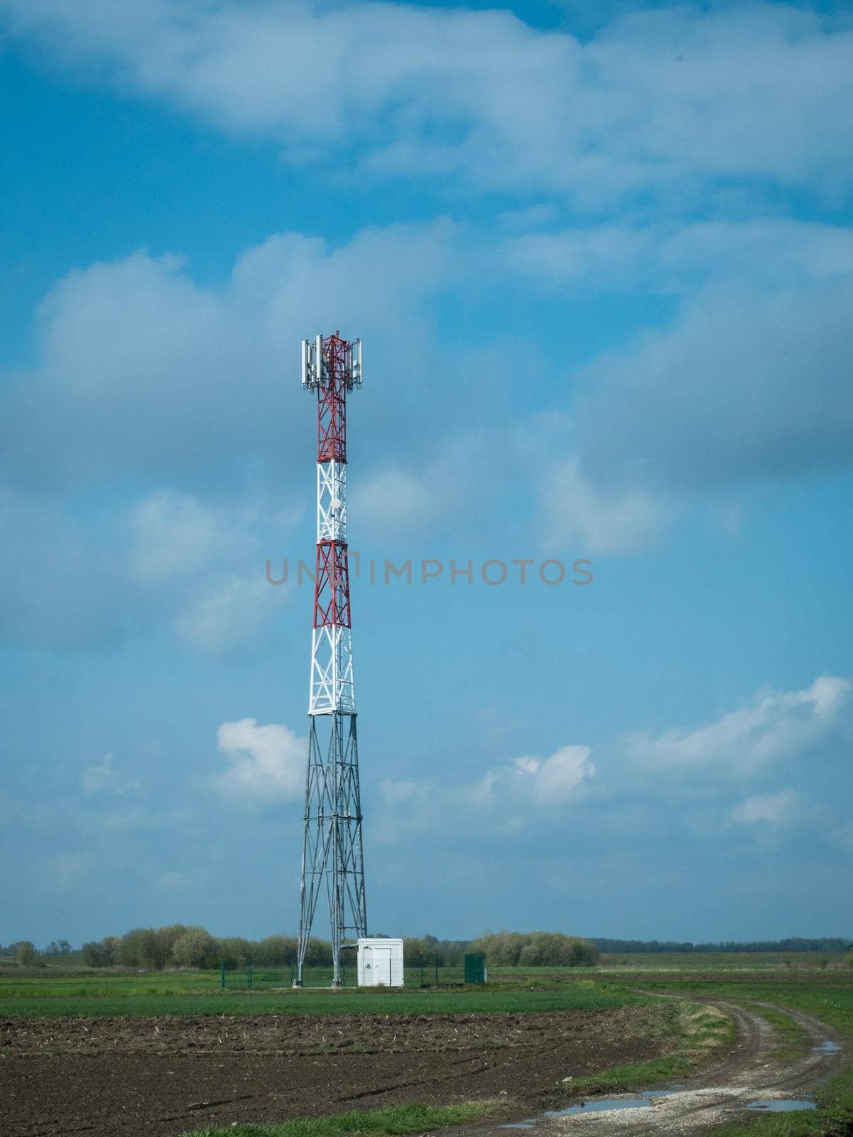 G5 cell phone tower base station against blue sky with clouds. Waves might increase the risk of health care issues.