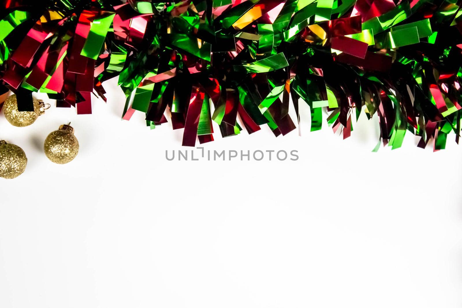 Christmas composition with green tinsel and golden decorations on a white background, copy space.