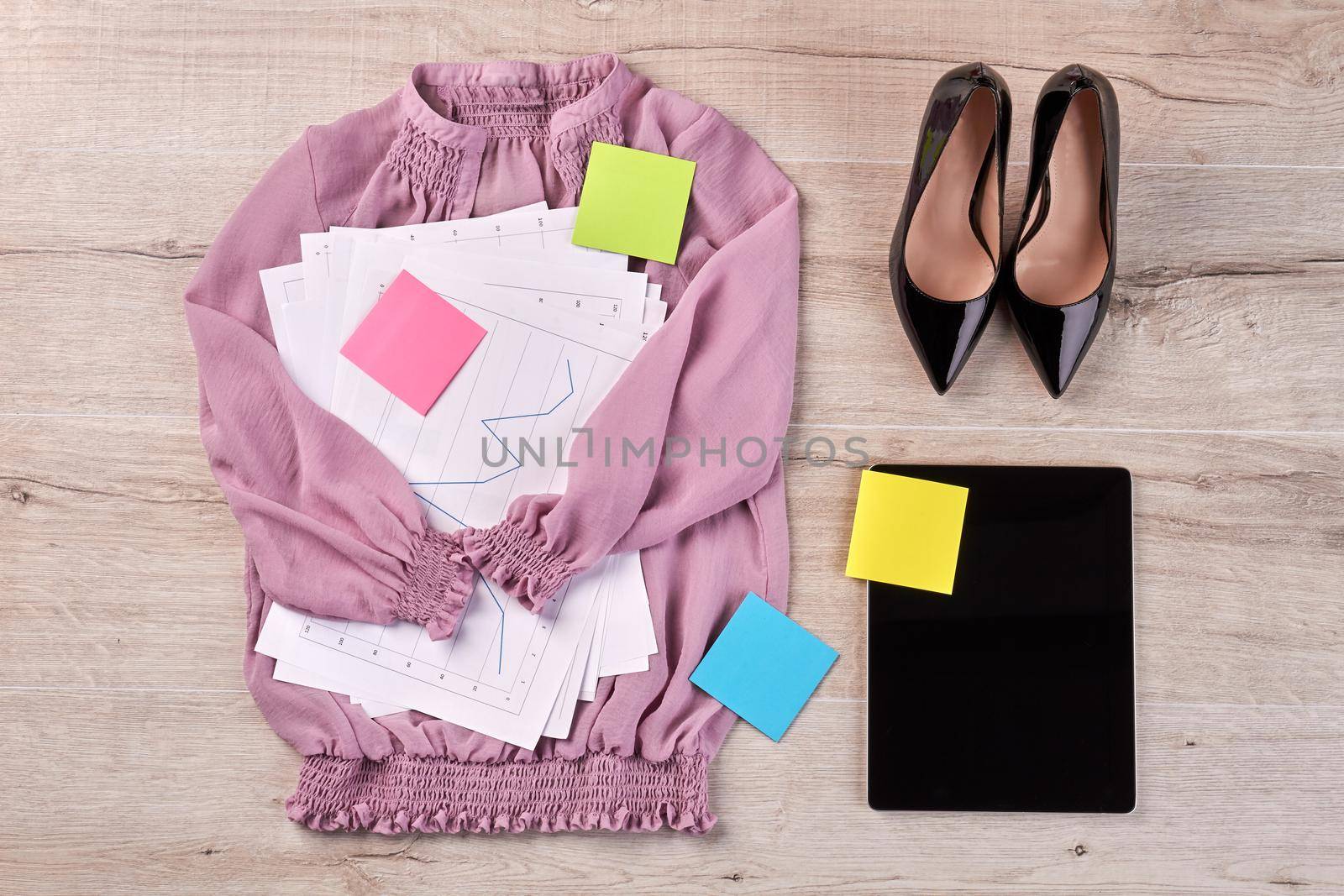 Purple blouse with work papers and black shoes. Top view flat lay.