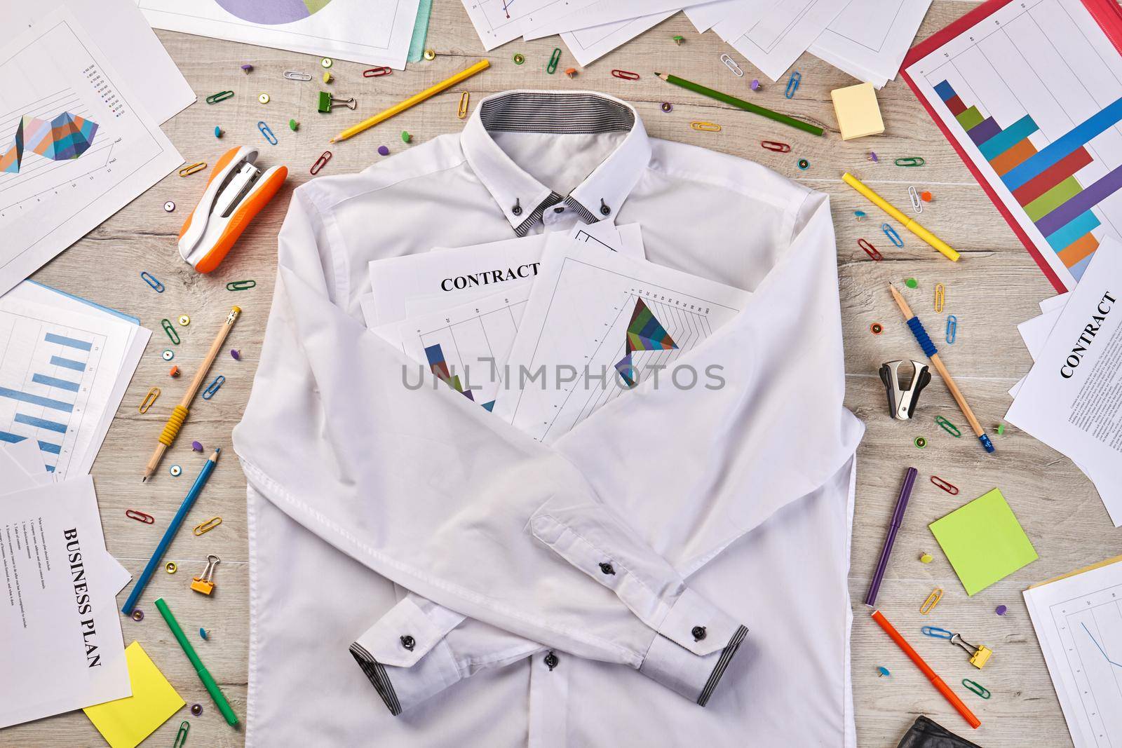 Top view white shirt with stationery workdesk stuff. Paperclips staplers pens etc.