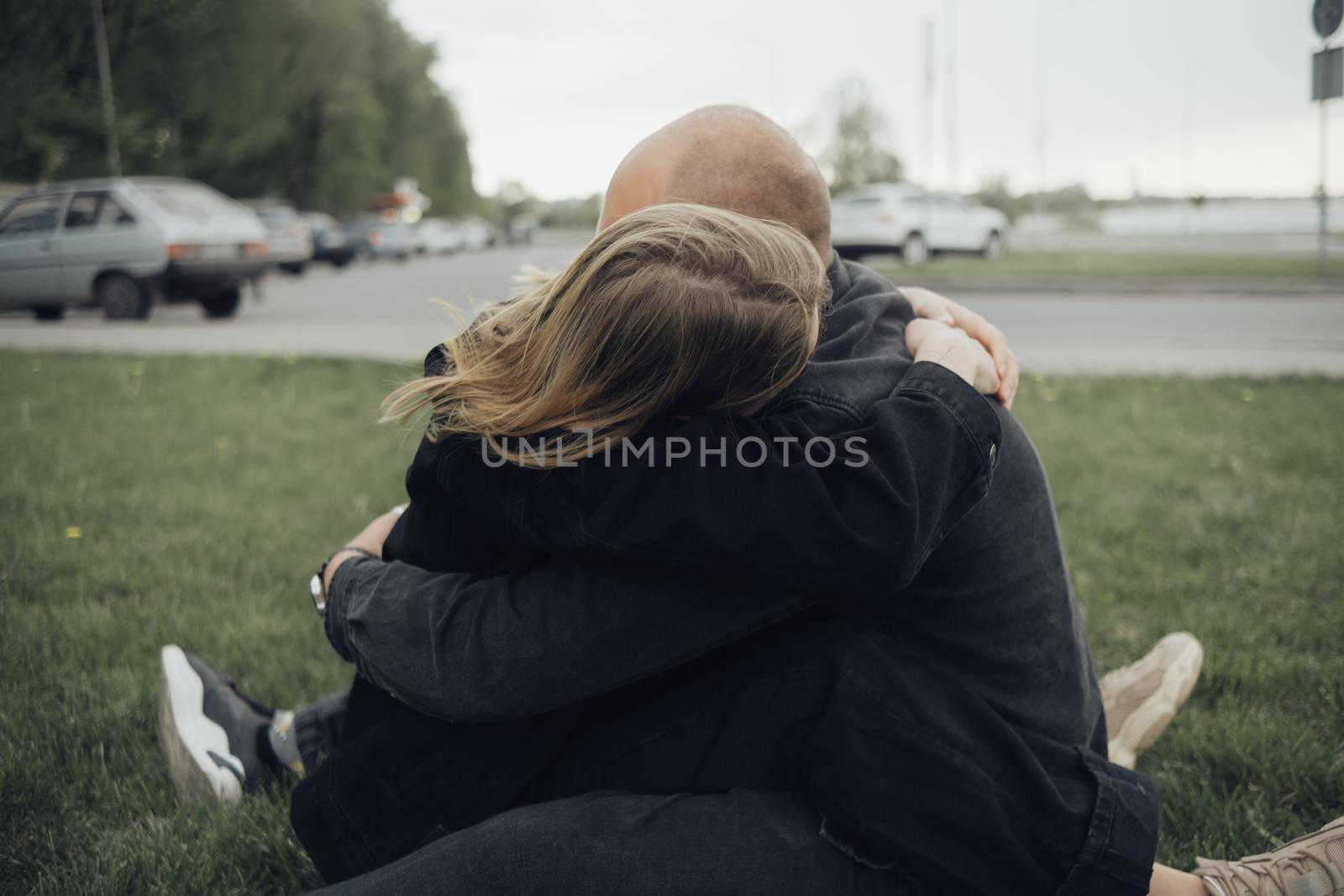 lovers hug tightly sitting on the grass by Symonenko