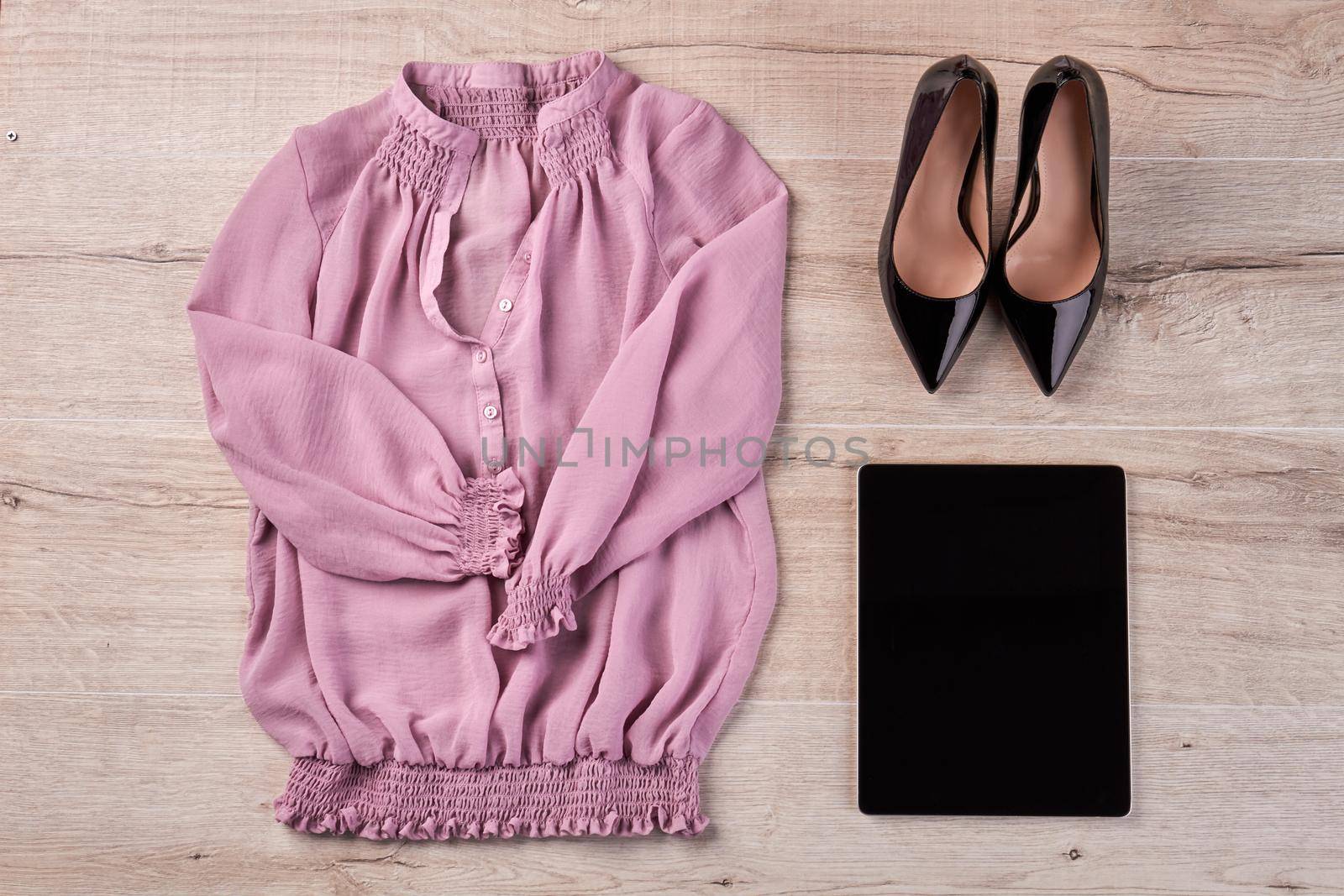 Shoes with blouse and tablet on white wooden desk. Top view flat lay.