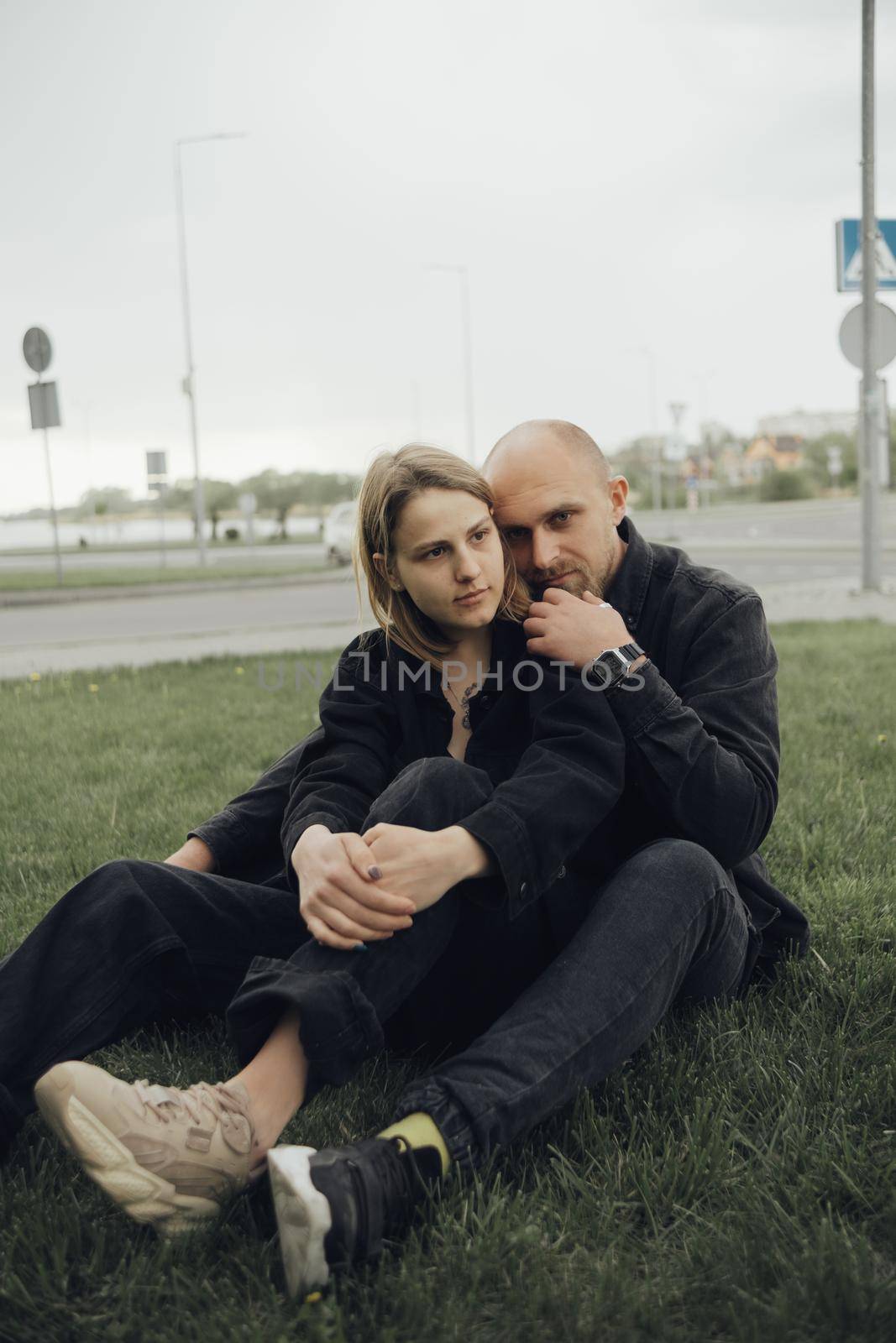 lovers hug sitting on the grass and look into the camera