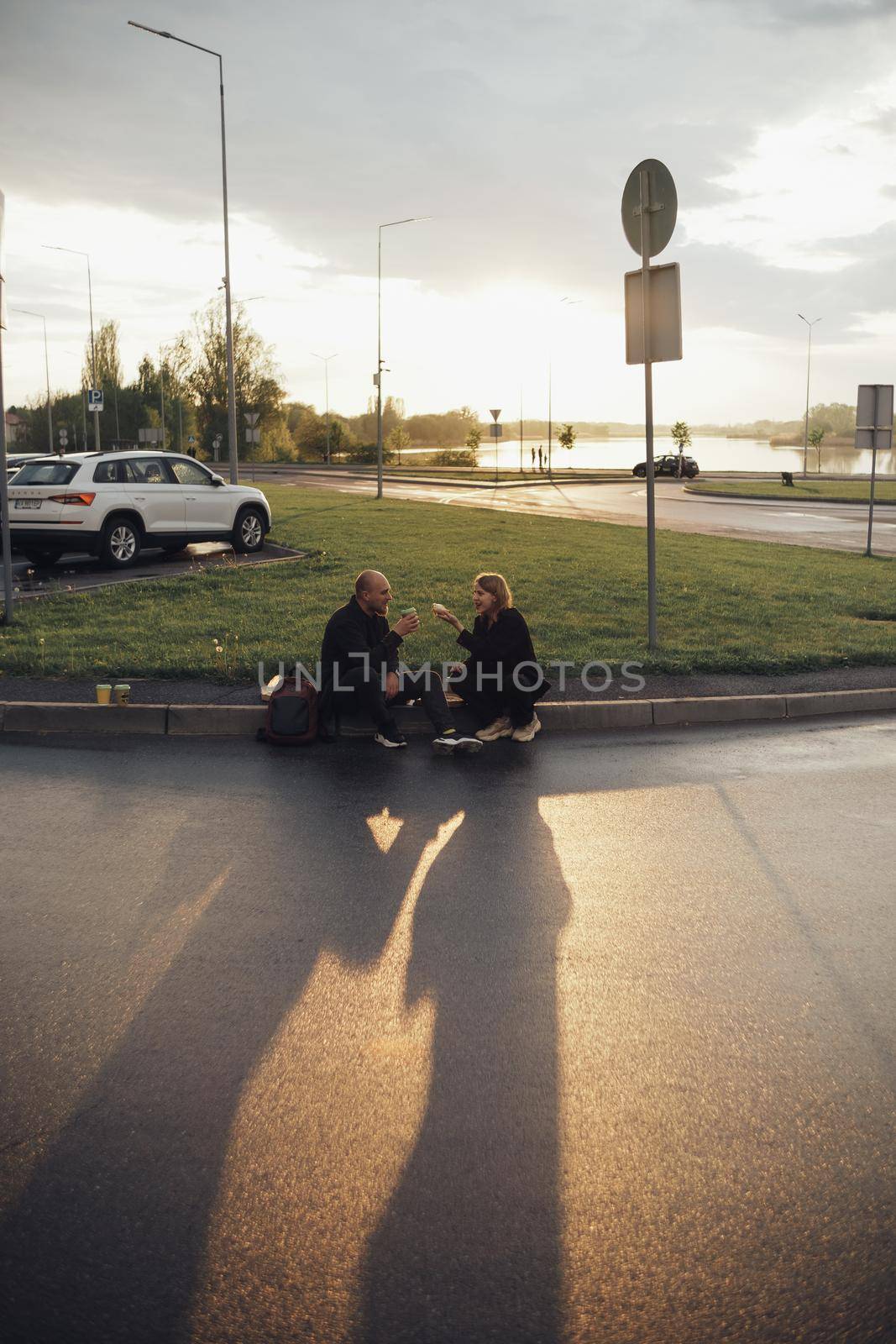 lovers eat pizza sitting on the lawn during sunset