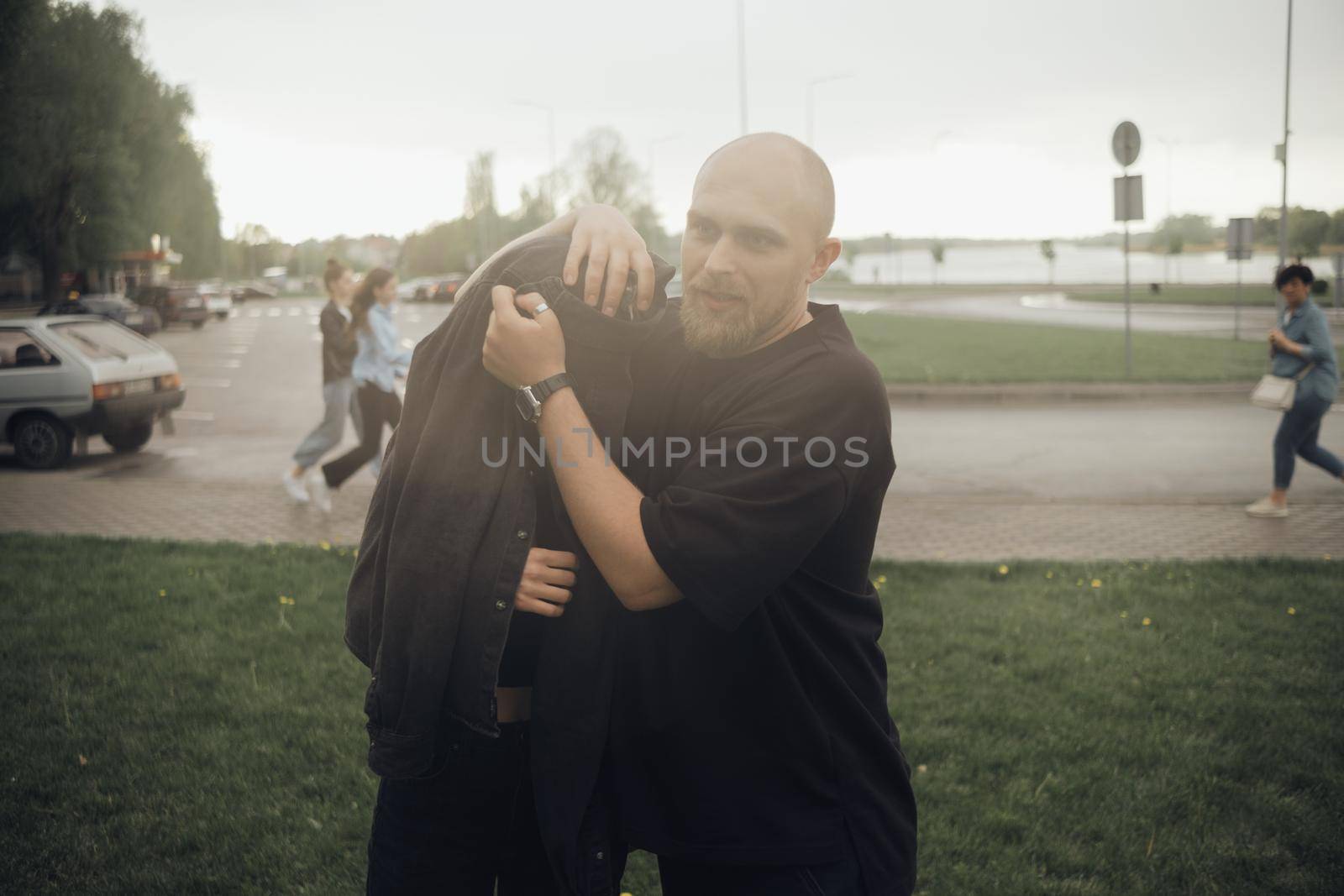 a couple in love is fleeing the rain. the guy covers the girl with his jacket by Symonenko