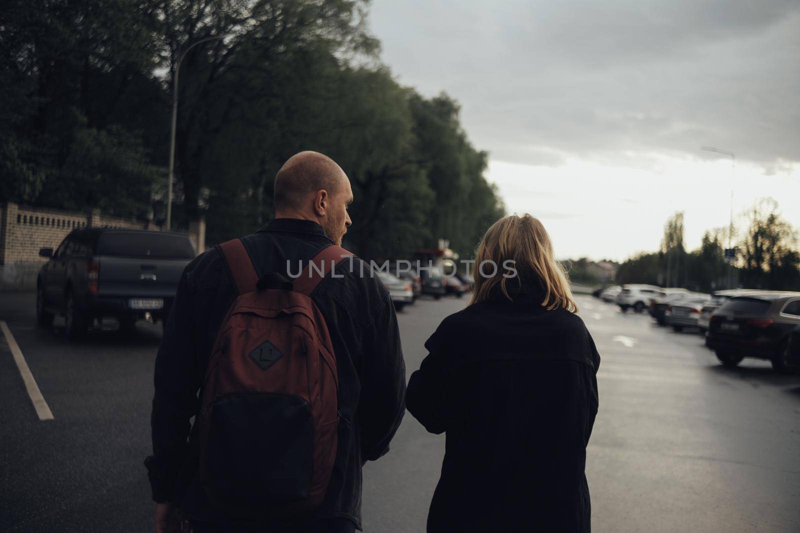 the lovers are coming. view from the back. the guy has a backpack on his back by Symonenko