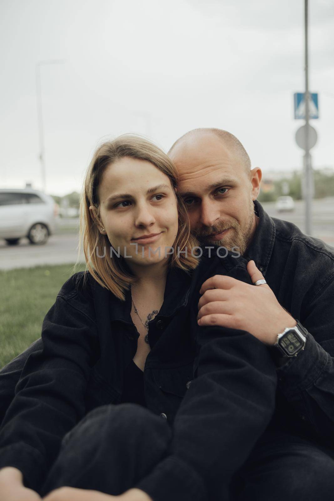 lovers hug sitting on the grass and look into the camera by Symonenko