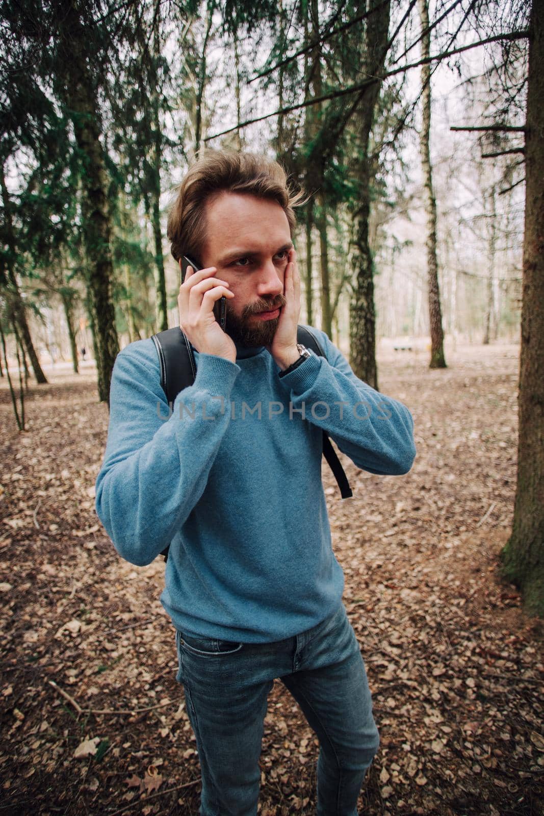Young adult man talking on the phone standing over white brick wall stressed with hand on head, shocked with shame and surprise face, angry and frustrated. Fear and upset for mistake.