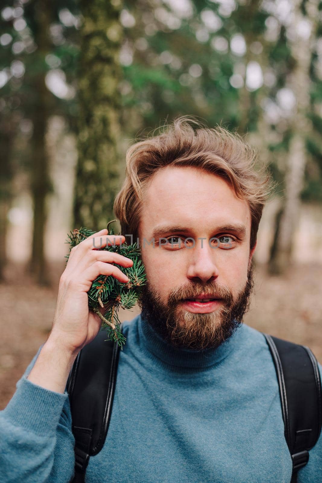 Young man laughing while talking on phone in forest with trees