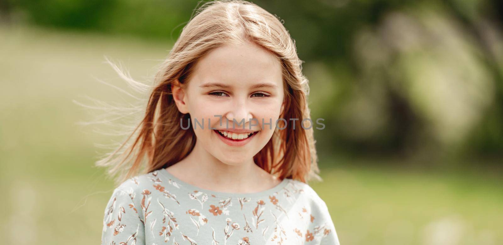 Little girl smiling in sunny spring day outdoors portrait. Cute child kid at nature