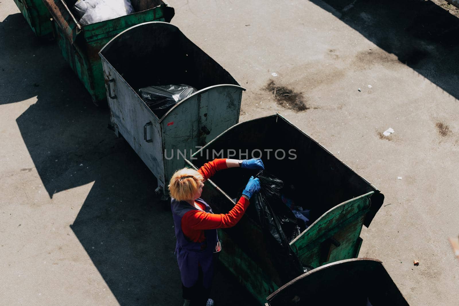 An old woman throws out trash. Trash can. The outside. Odessa City, Ukraine, May 2019. by Symonenko