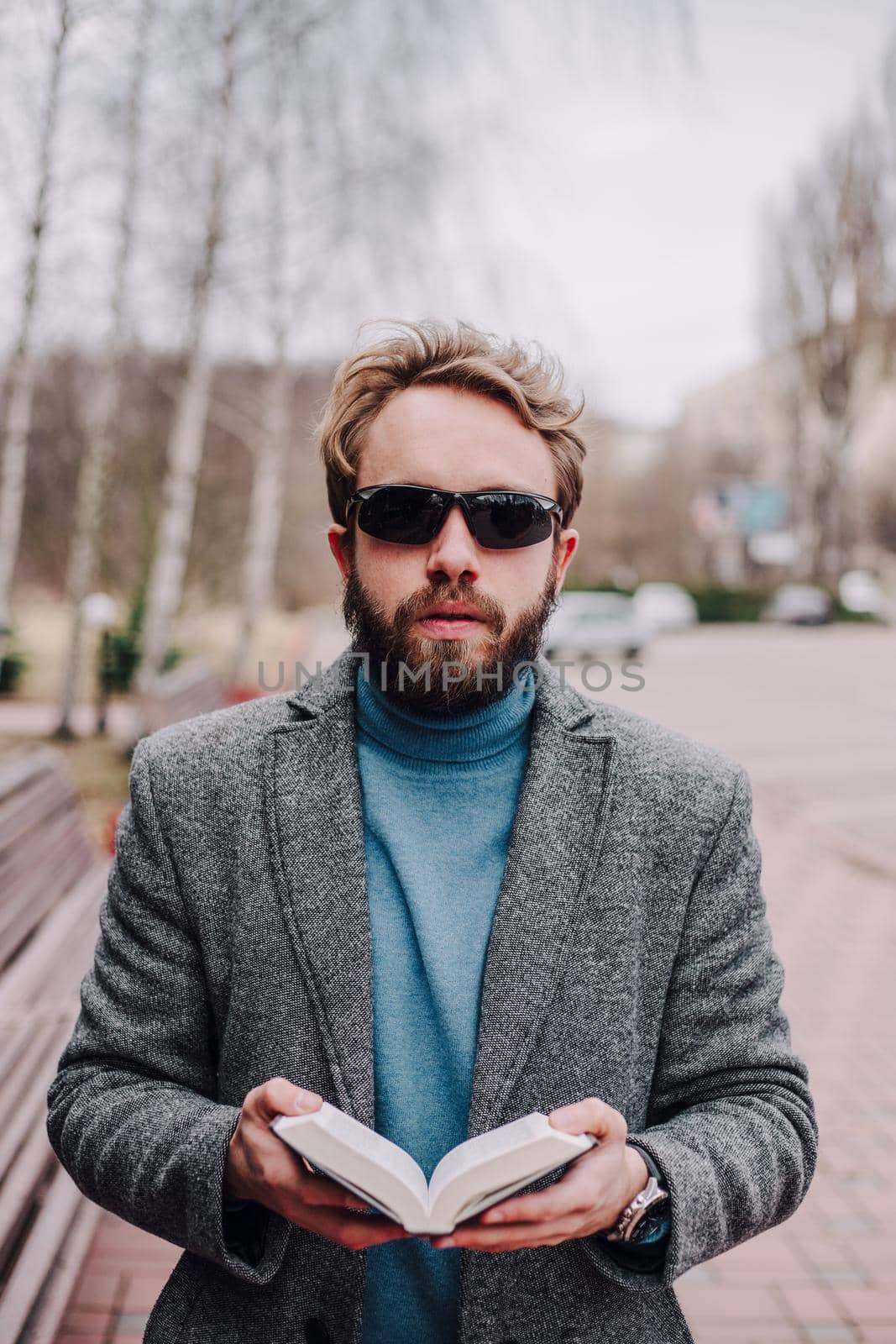 Portrait handsome bearded man wearing glasses blue shirt.Man near university library, reading book and relaxing. Blurred background.Horizontal, film effect.