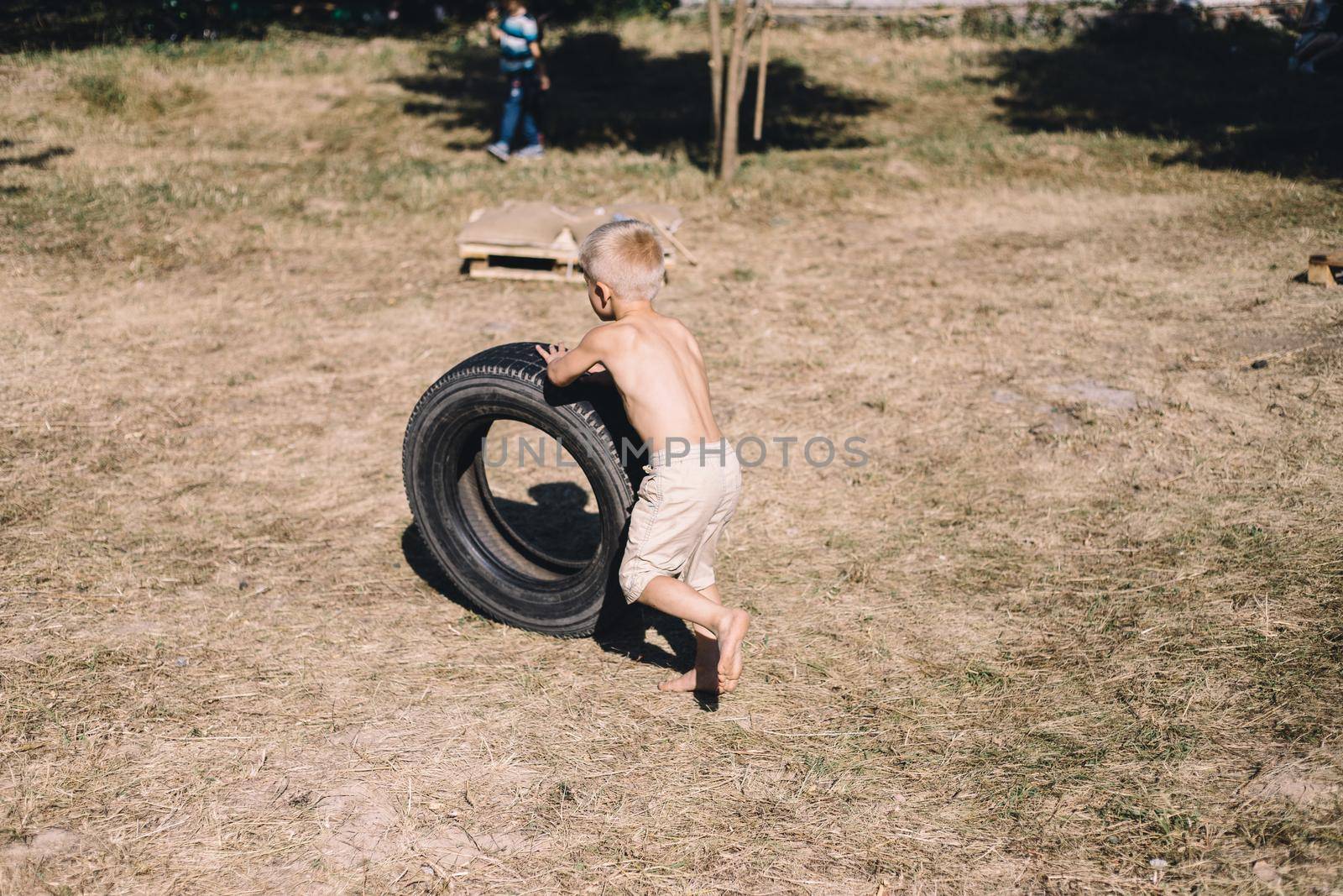 the naked boy playing with the old tire by Symonenko