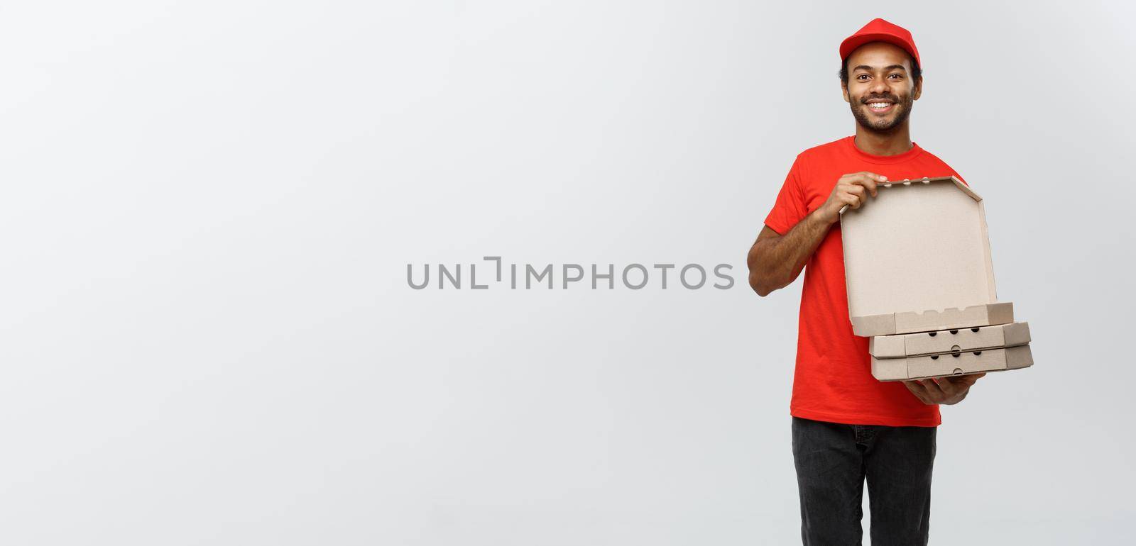 Delivery Concept - Portrait of Handsome African American Pizza delivery man. Isolated on Grey studio Background. Copy Space. by Benzoix