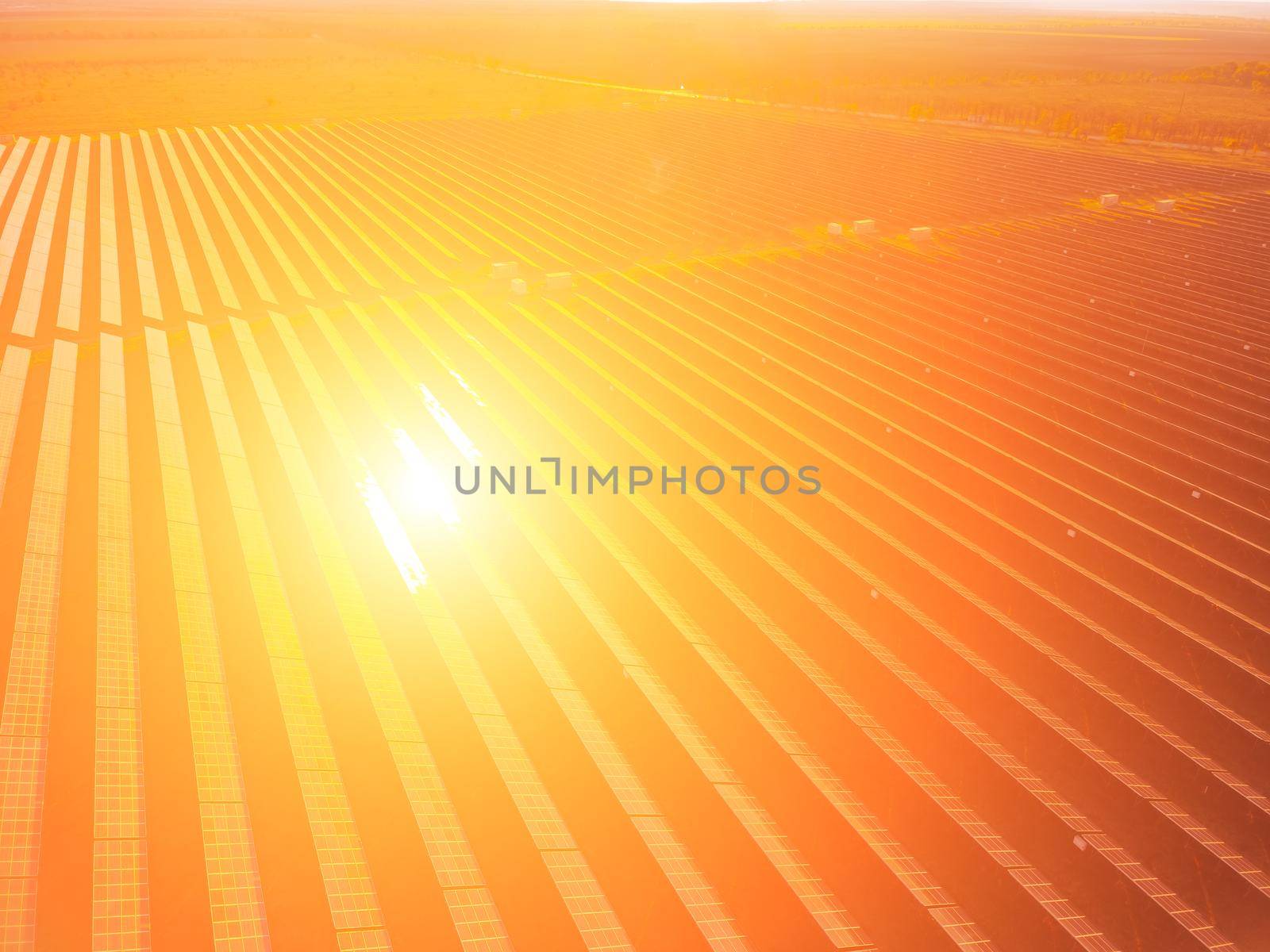 Aerial top view of a solar panels power plant. Photovoltaic solar panels at sunrise and sunset in countryside from above. Modern technology, climate care, earth saving, renewable energy concept