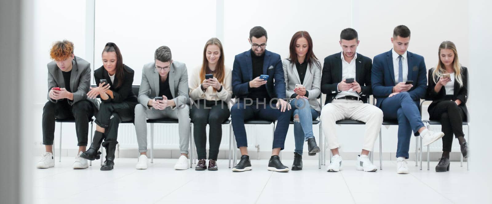 group of diverse young business people looking at their smartphone screens. by asdf
