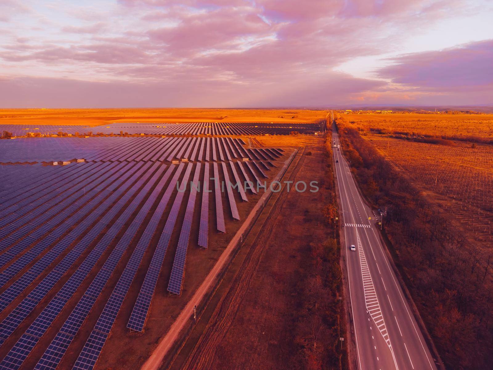 Aerial top view of a solar panels power plant. Photovoltaic solar panels at sunrise and sunset in countryside from above. Modern technology, climate care, earth saving, renewable energy concept