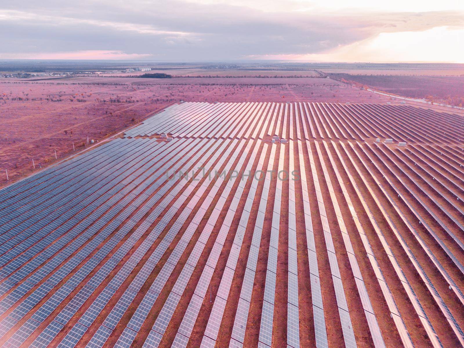 Aerial top view of a solar panels power plant. Photovoltaic solar panels at sunrise and sunset in countryside from above. Modern technology, climate care, earth saving, renewable energy concept