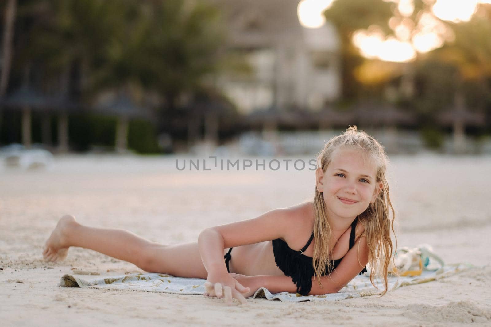 A charming little girl is lying on the beach and drawing on the sand.A little girl lies on the beach of the island of Mauritius.