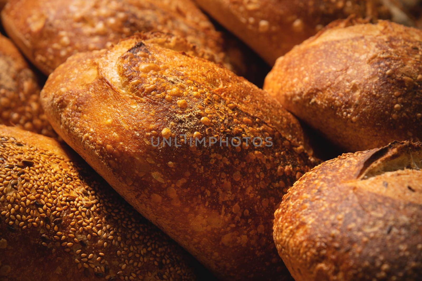 Fresh crispy hot delicious craft artisan bread. Many loaves lie on a wooden pallet.