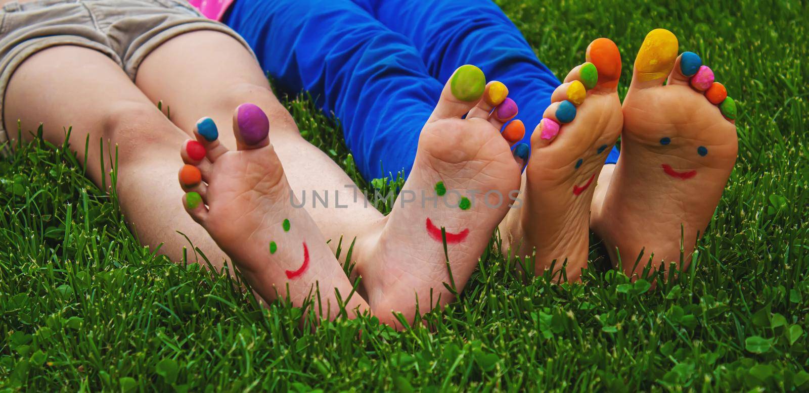 Children's feet with a pattern of paints smile on the green grass. Selective focus..child