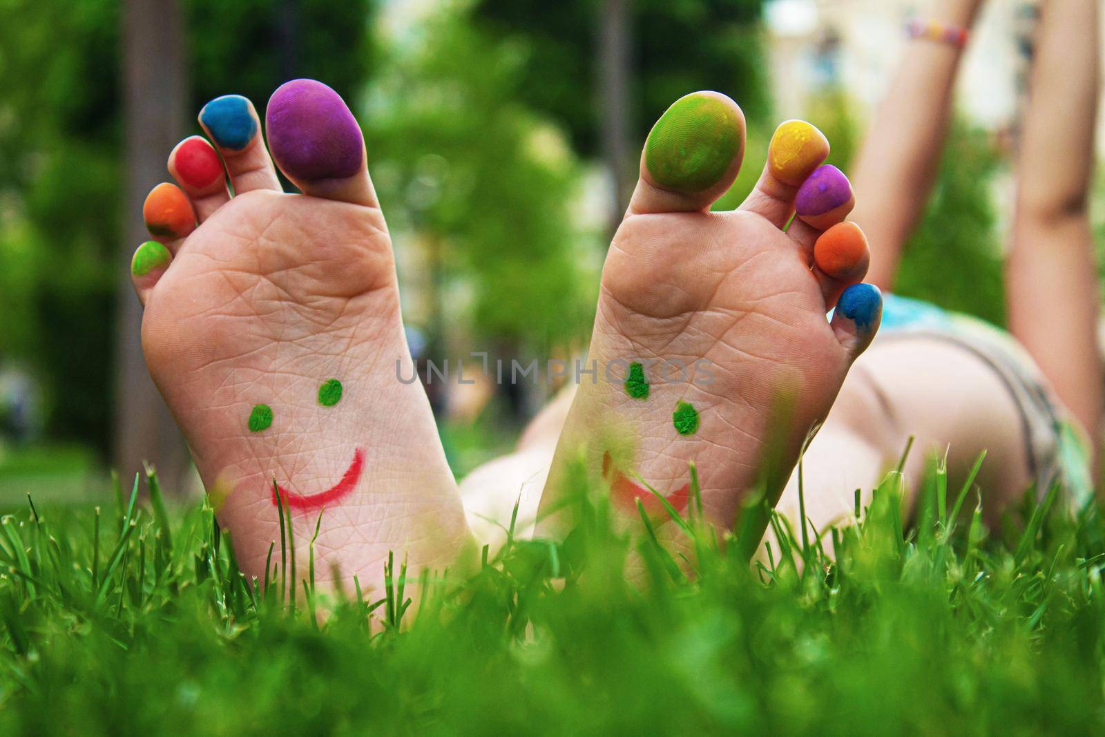 Children's feet with a pattern of paints smile on the green grass. Selective focus..child