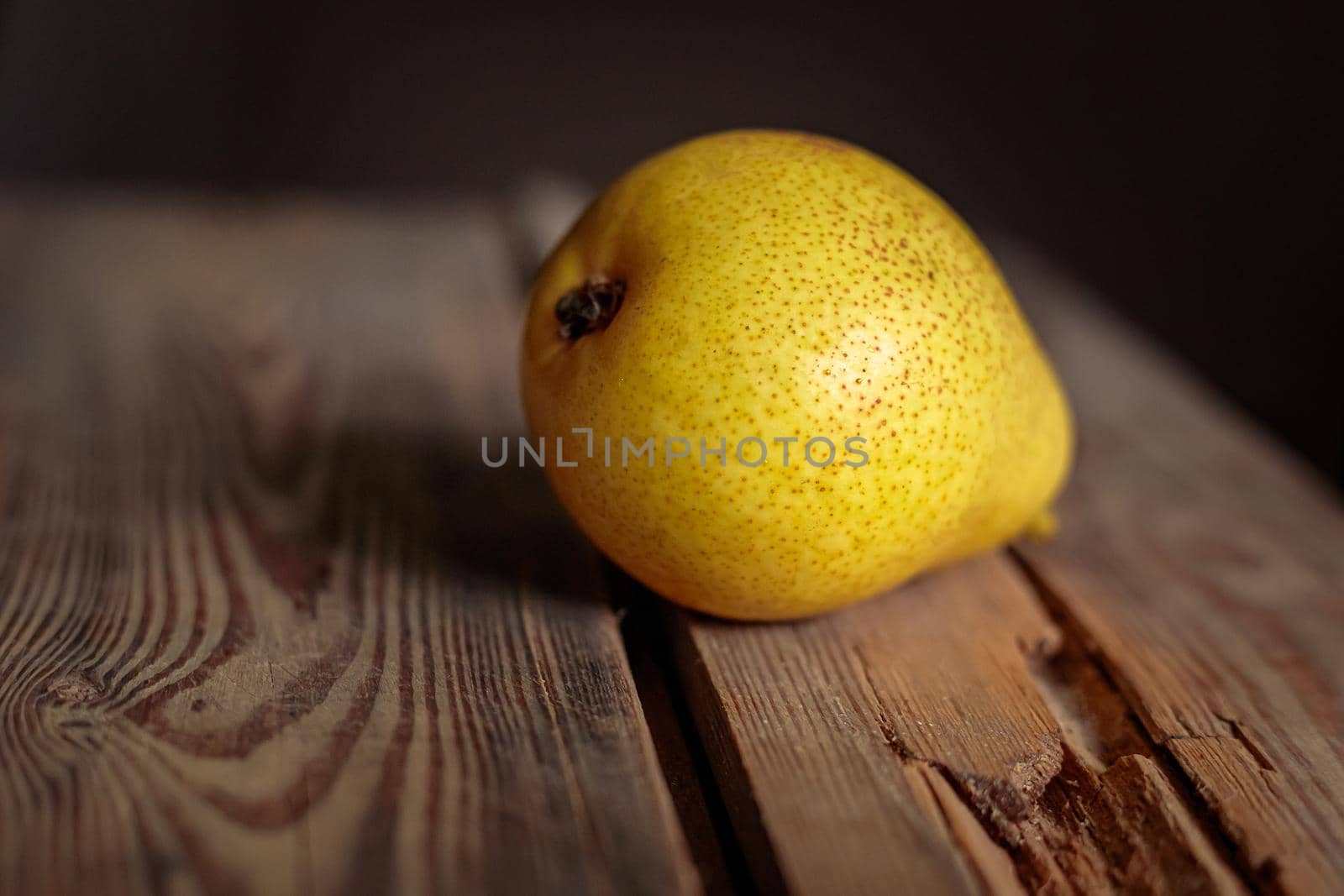 Juicy yellow pear on a wooden background from old boards in a low key. Ripe pear for a healthy diet.