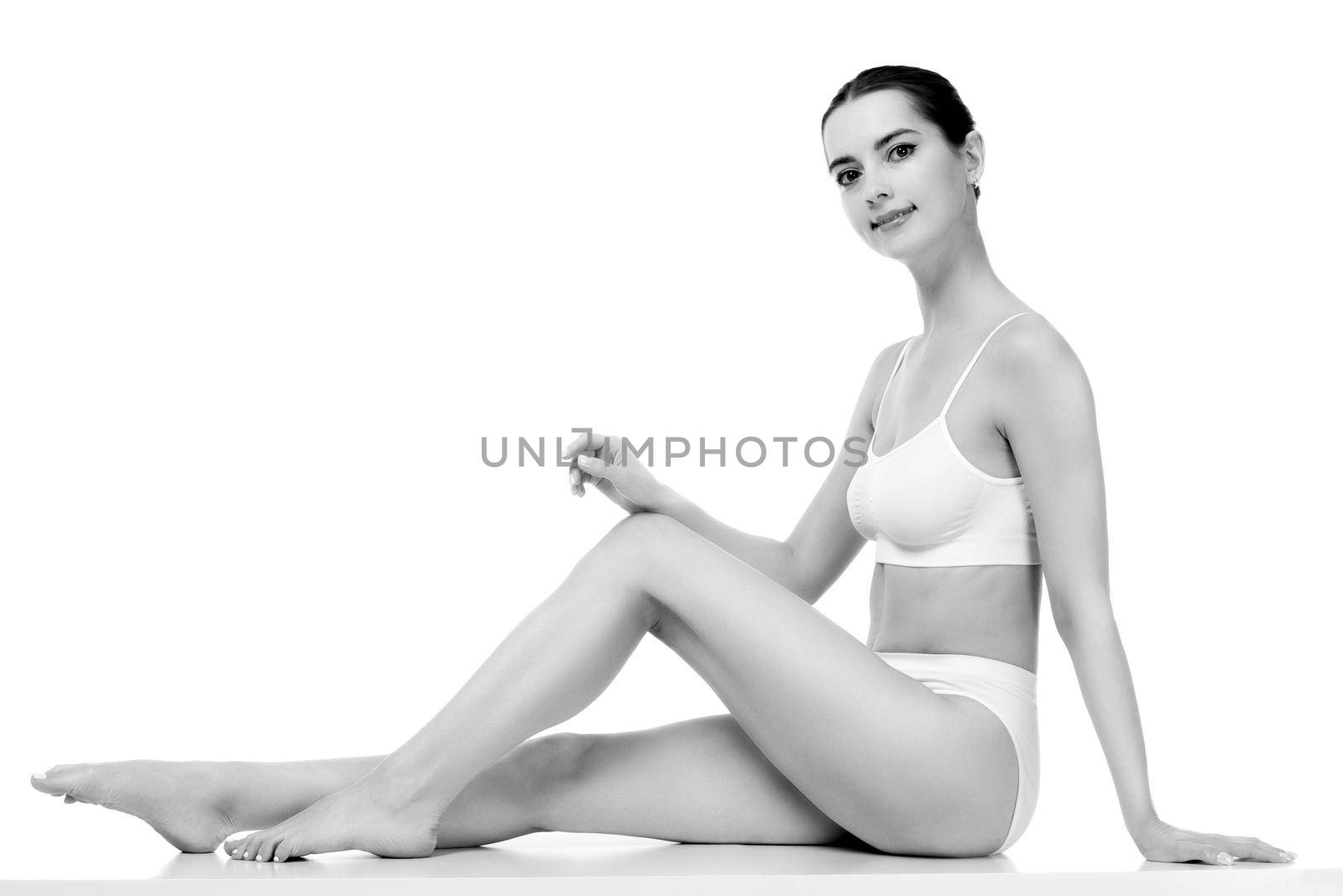 Pretty woman with slim beautiful body sitting against white background, isolated by Nobilior