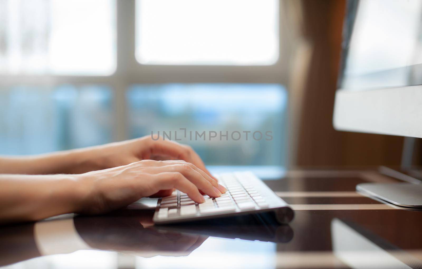 Female hands typing text on the keyboard while exchanging messages with friends via social networks using a computer laptop. A female office worker checks her email while sitting at a desk.